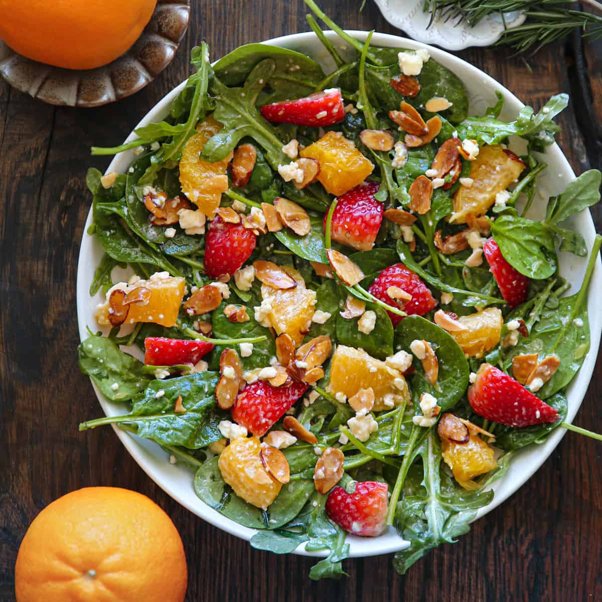 Strawberry Orange Salad with Spinach, Arugula, Toasted Sliced Almonds, and Feta Cheese - in a white bowl.