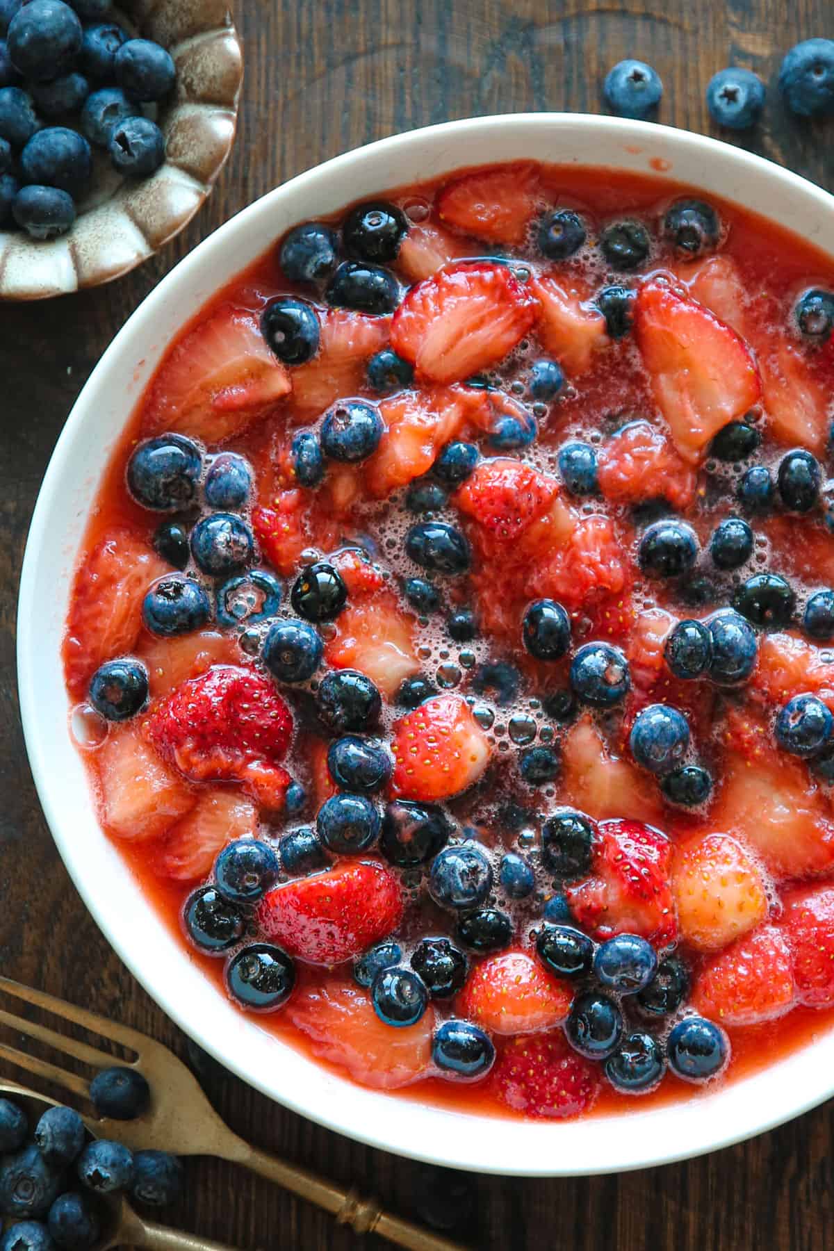 cooked strawberries with blueberries - in a white bowl.