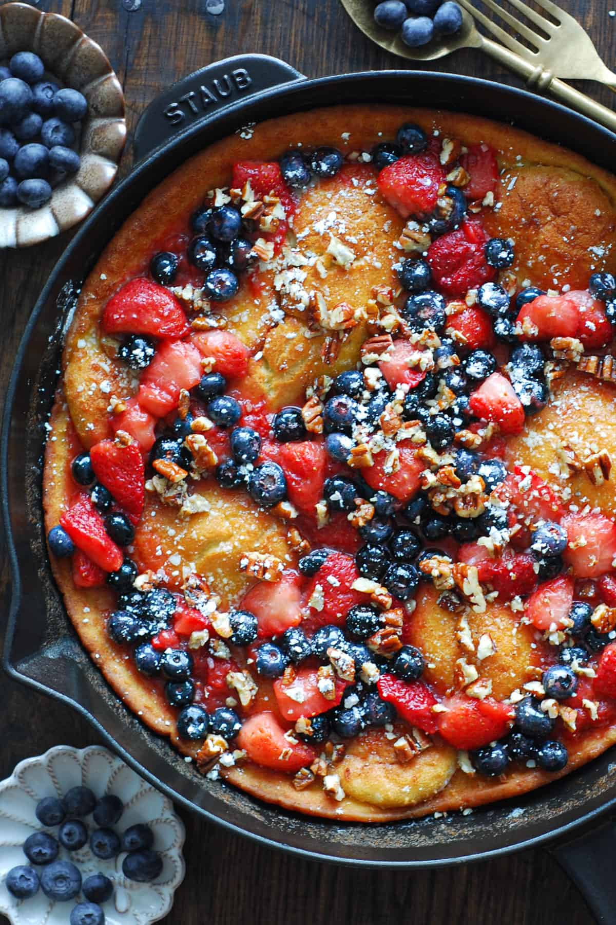 Dutch Baby Pancake with Cooked Strawberries, Blueberries, and Pecans - in a cast iron skillet.