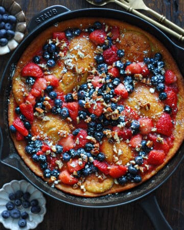 dutch baby pancake with strawberries and blueberries - in a cast iron skillet.