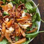 Pear Spinach Salad with Goat Cheese, Pecans, and Honey-Lemon Dressing - in a white bowl.