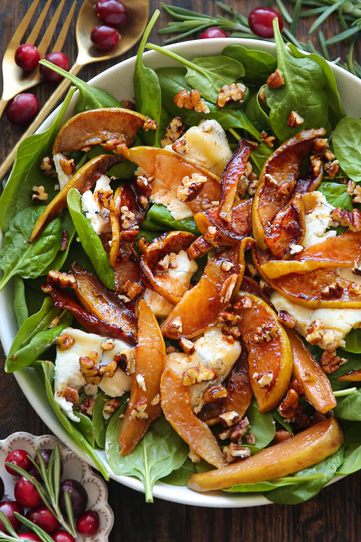 Pear Spinach Salad with Goat Cheese, Pecans, and Honey-Lemon Dressing - in a white bowl.