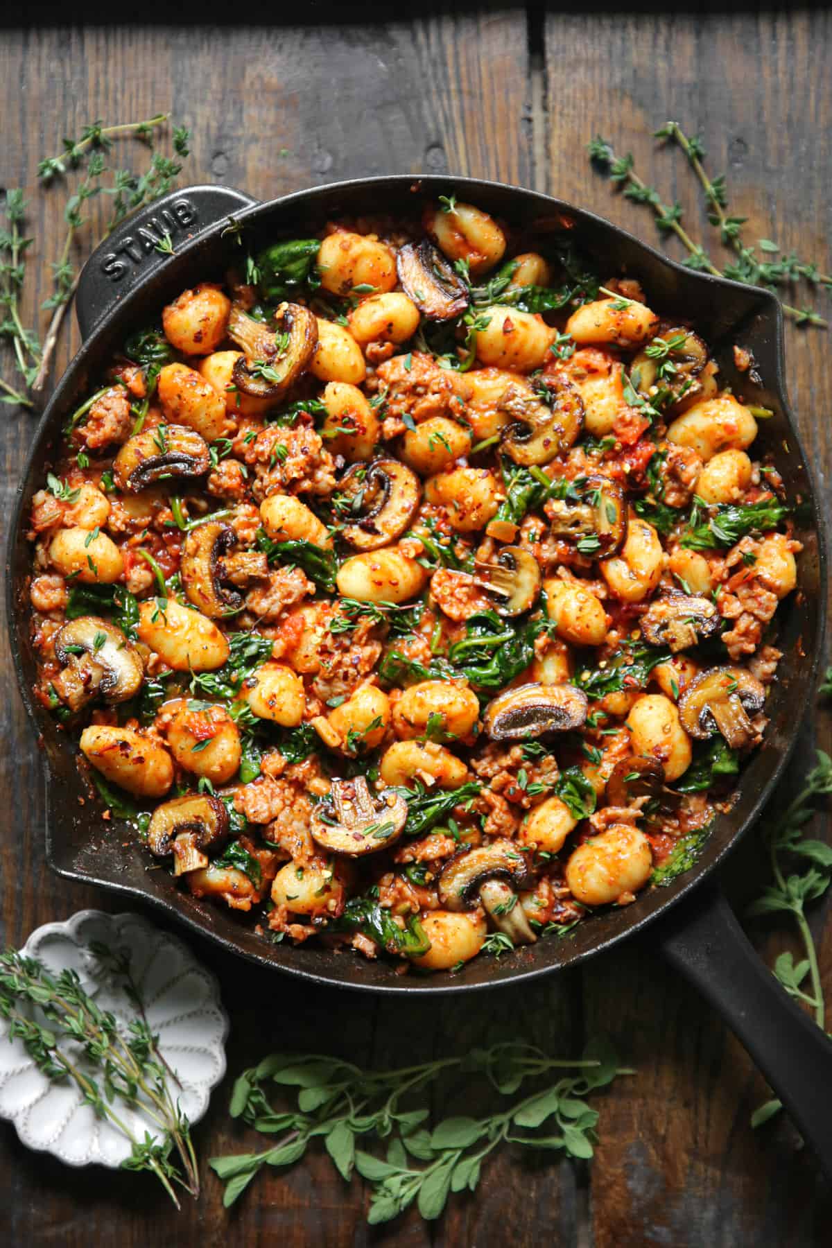 gnocchi with tomato sauce, sausage, spinach, and mushrooms in a cast iron skillet.