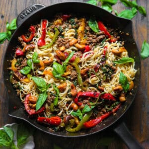 Ramen Noodle Stir Fry with Bell Peppers, Spinach, Cashews, Sesame Seeds, and Ground Beef - in a cast iron skillet.
