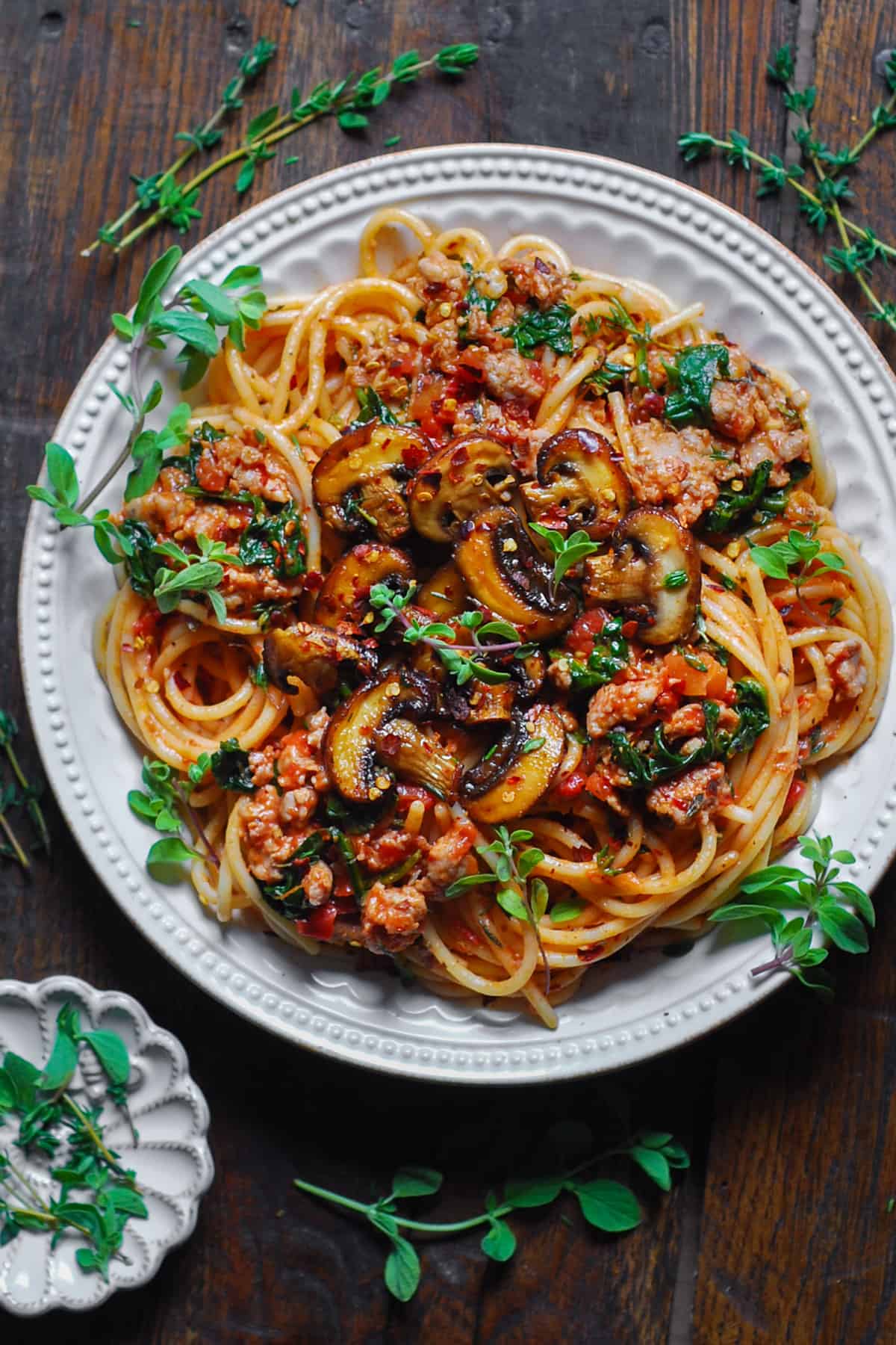 Sausage Mushroom Pasta with Tomatoes and Spinach - on a white plate.