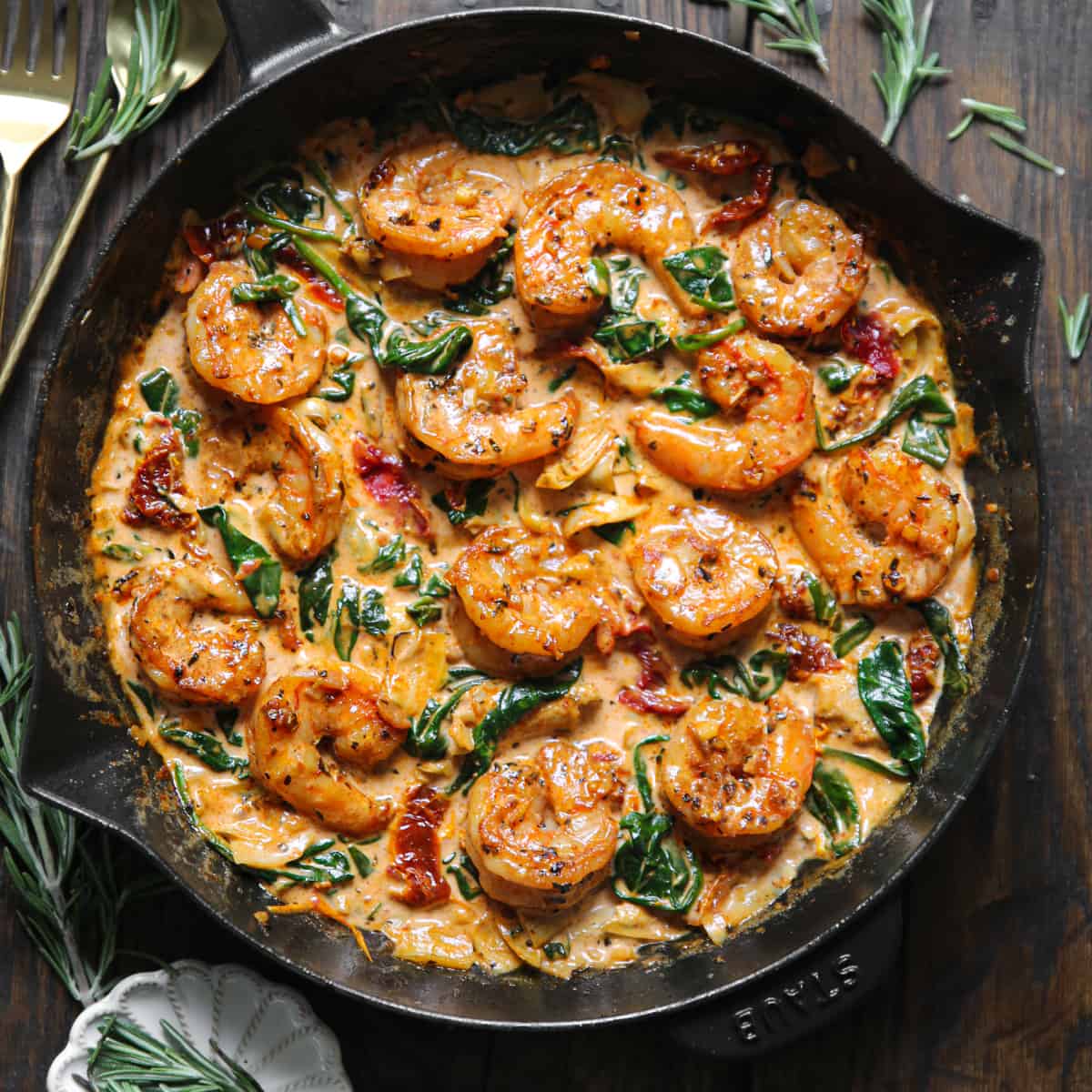 Creamy Tuscan Shrimp with Sun-Dried Tomatoes, Spinach, and Artichokes - in a cast iron skillet.