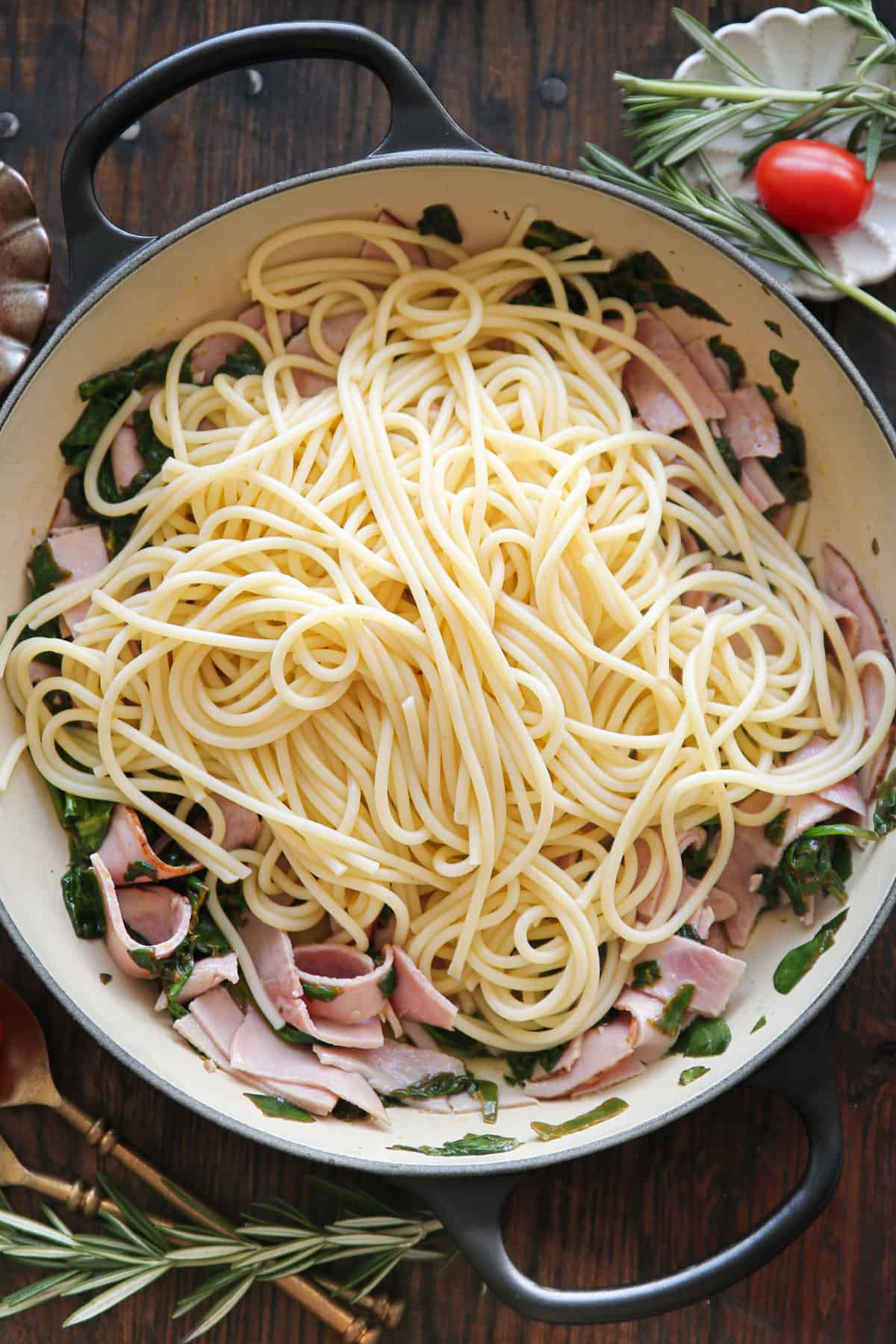 wilted spinach, sliced ham, and cooked spaghetti - in a cooking pan.