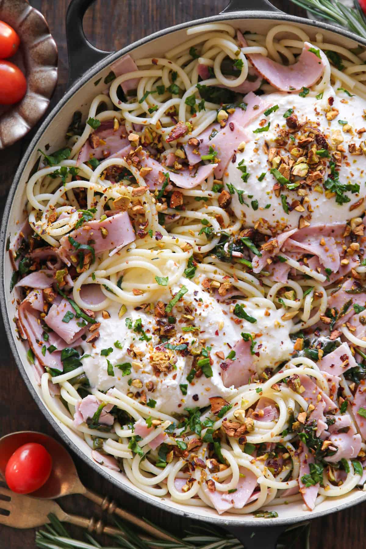 Ham spaghetti pasta with Burrata cheese, spinach, and chopped pistachios - in a cooking pan.