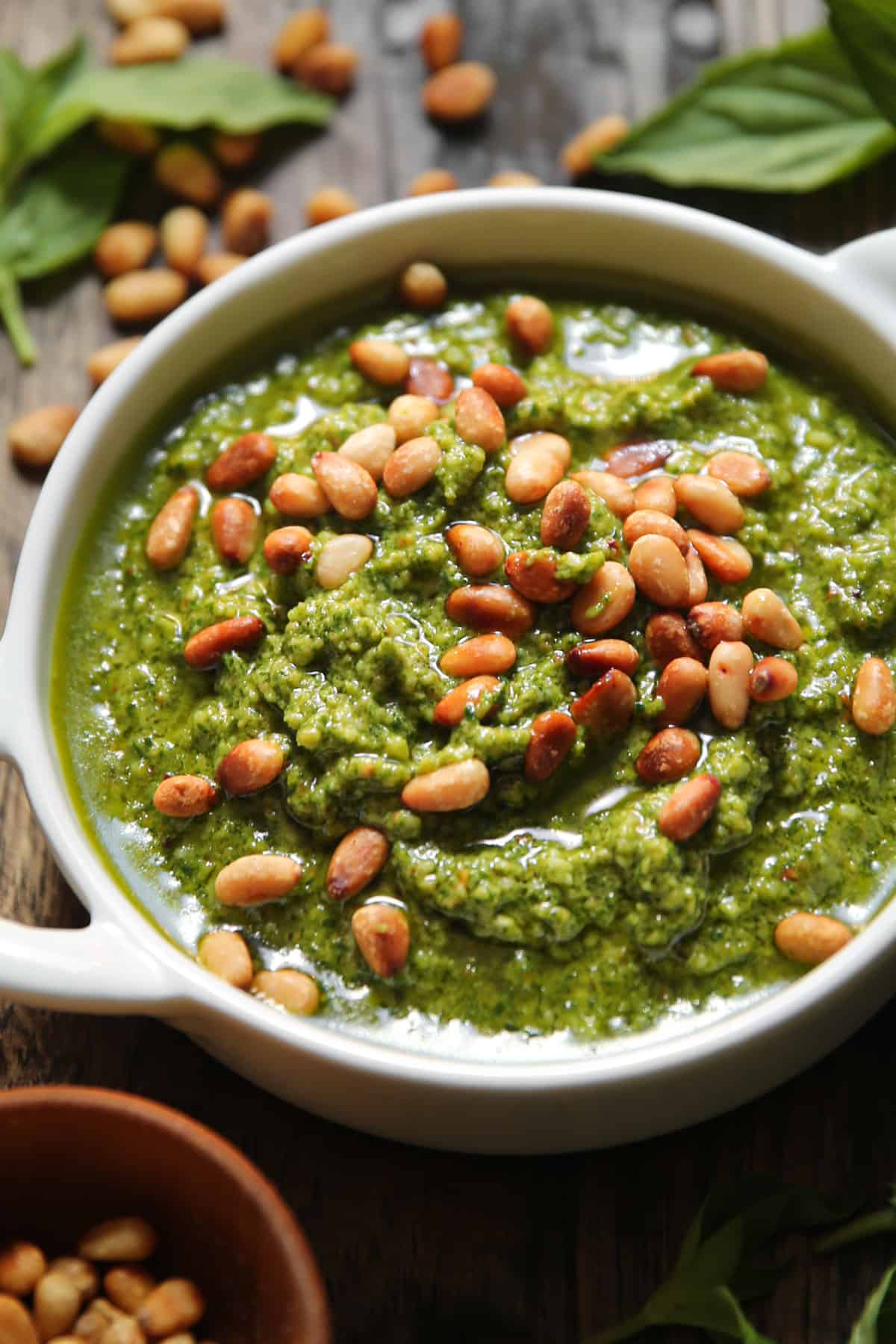 basil pesto with pine nuts on top in a small white serving dish.