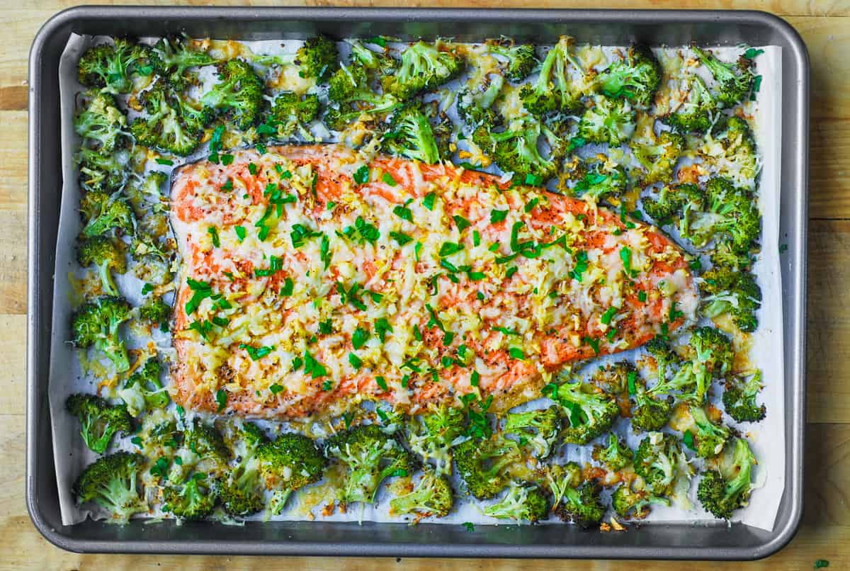 baked salmon and broccoli with minced garlic and shredded Parmesan Cheese on a sheet pan.