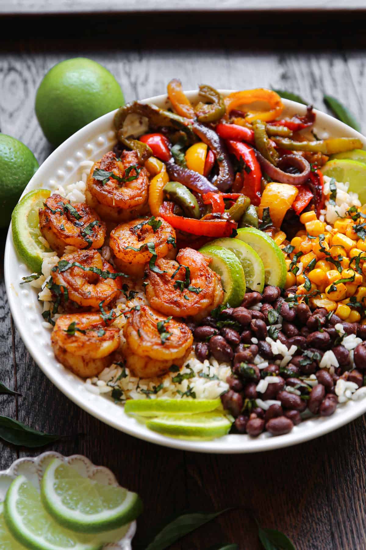 Shrimp Fajita bowl with bell peppers, red onions, black beans, corn, rice, and lime slices.