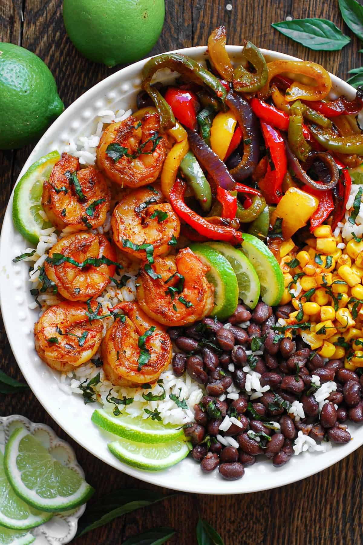 Shrimp Fajita bowl with bell peppers, red onions, black beans, corn, rice, and lime slices.