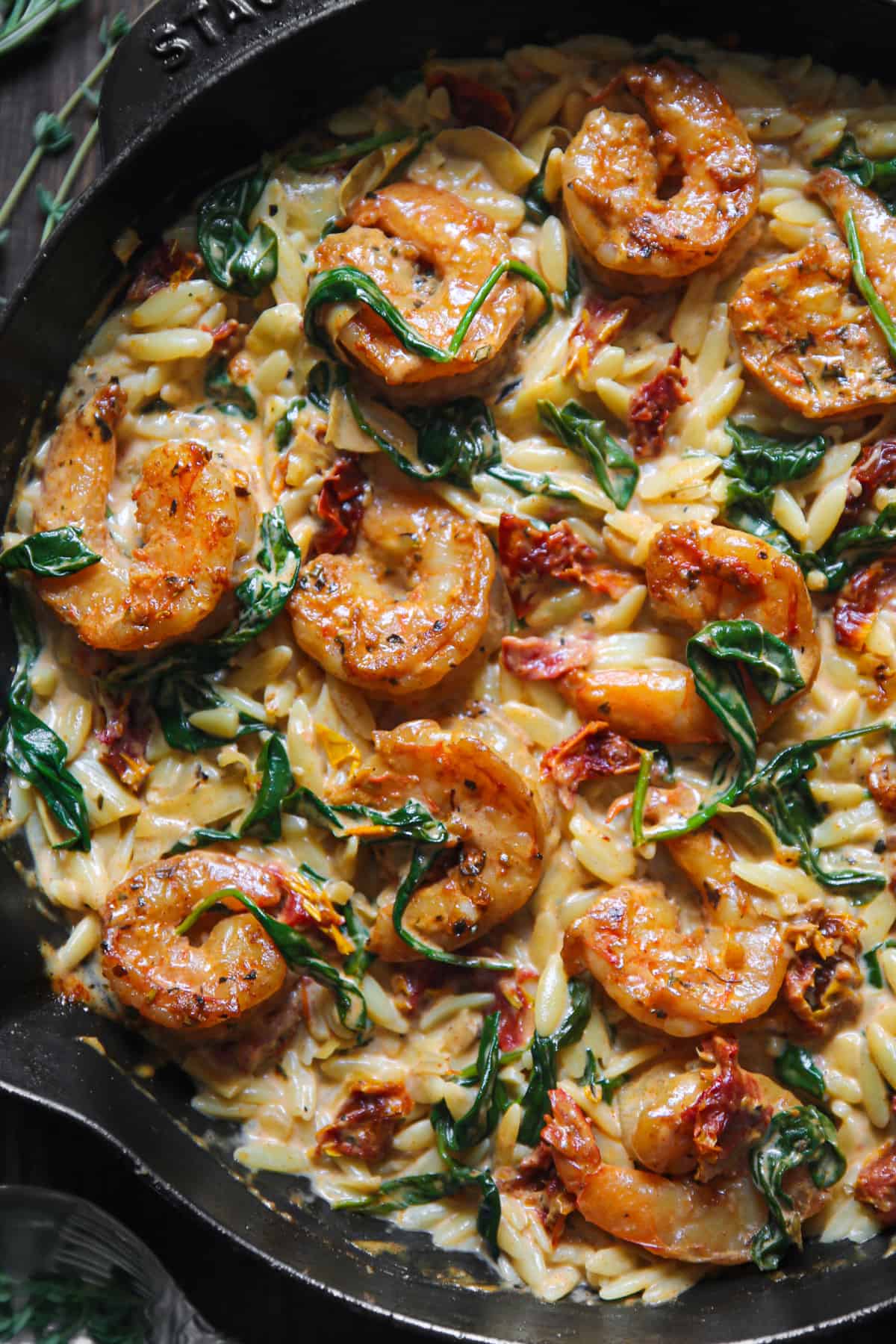 Creamy Shrimp Orzo with Spinach, Sun-Dried Tomatoes, and Artichokes - in a cast iron skillet.