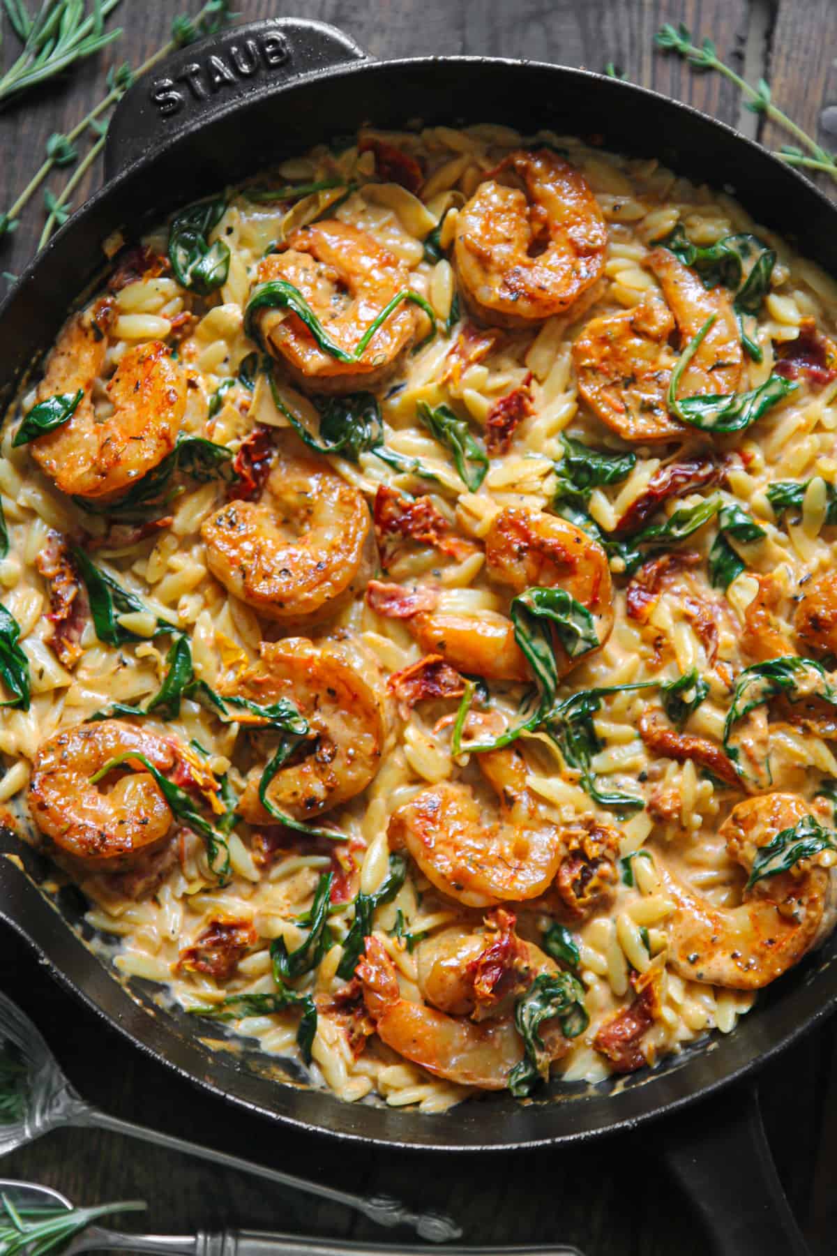 Creamy Shrimp Orzo with Spinach, Sun-Dried Tomatoes, and Artichokes - in a cast iron skillet.