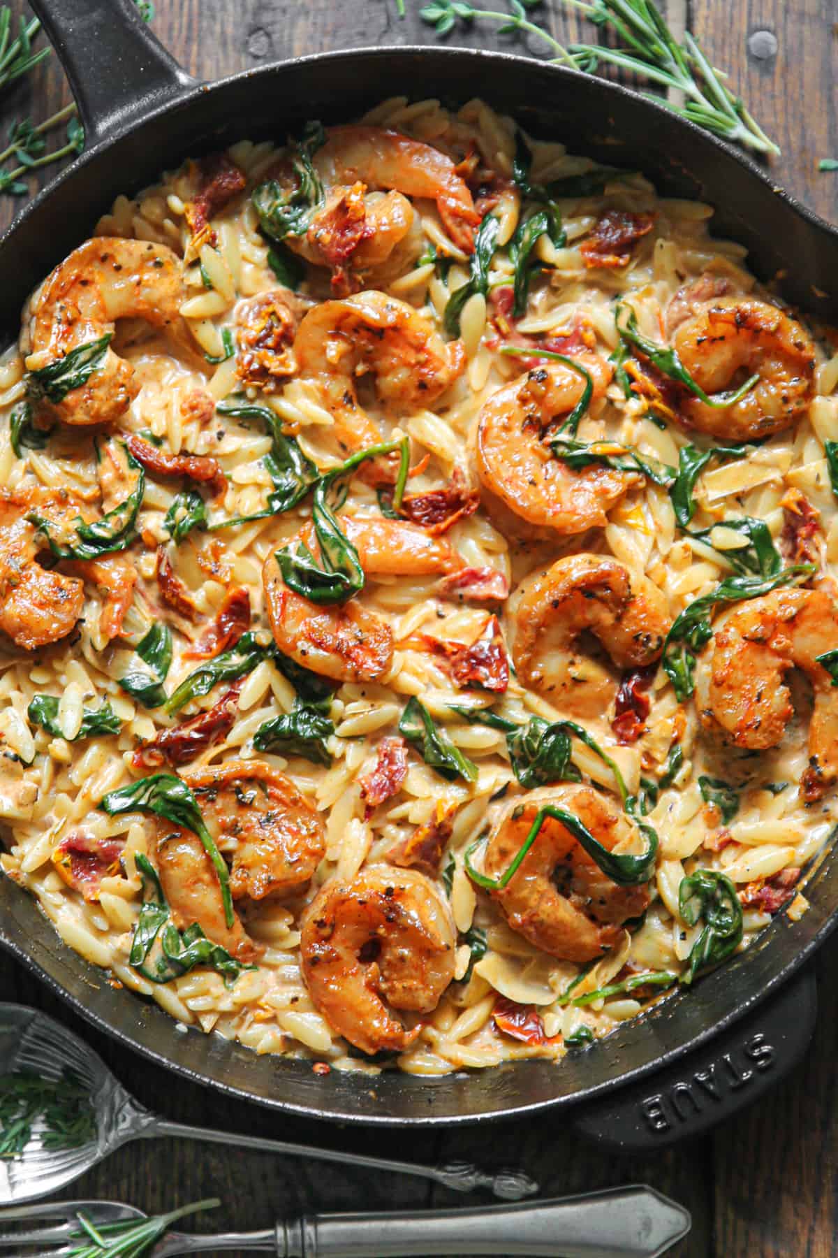 Creamy Shrimp Orzo with Sun-Dried Tomatoes, Spinach, Artichokes - in a cast iron skillet.