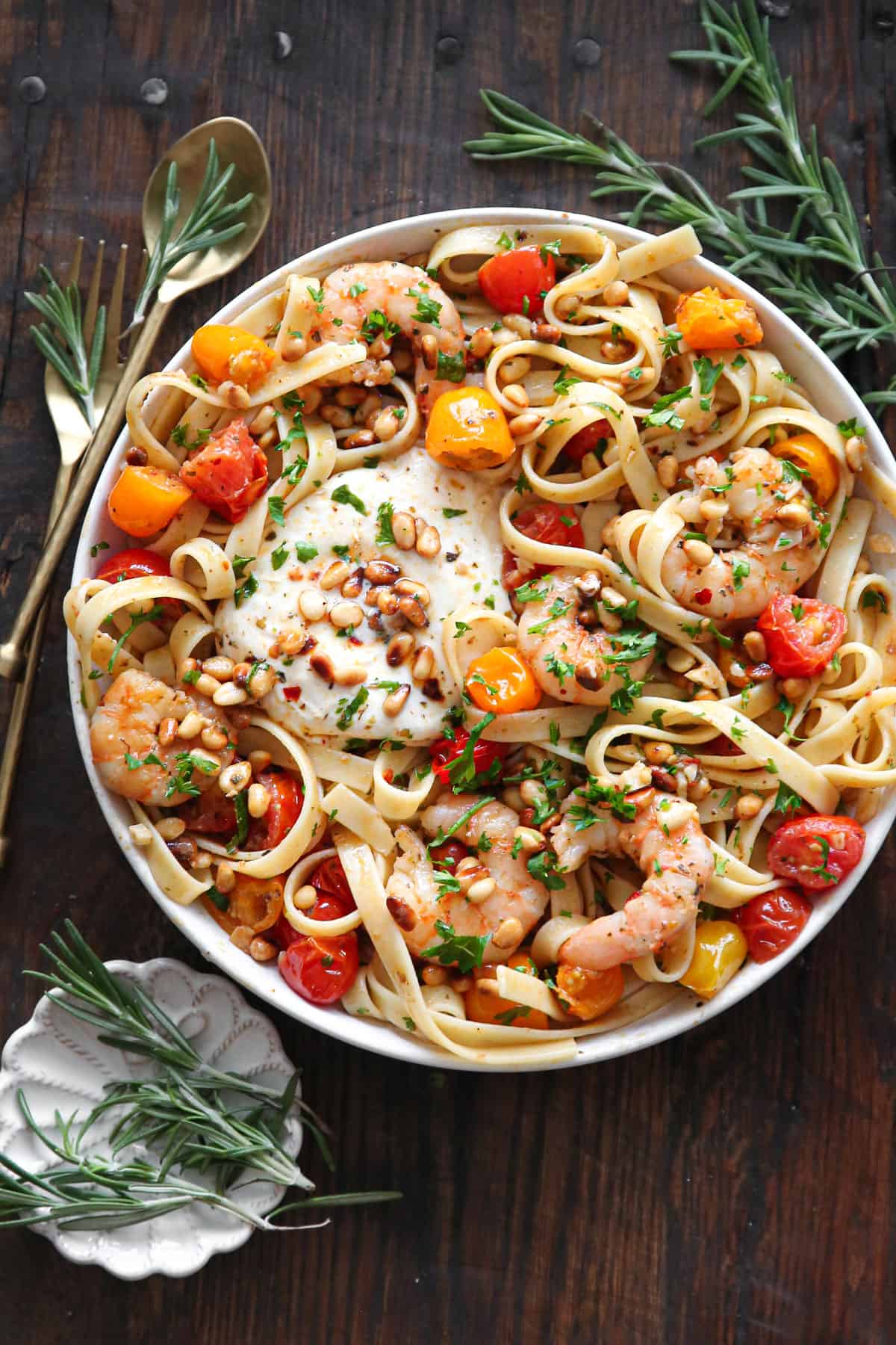 Mediterranean Shrimp Pasta with Cherry Tomatoes, Burrata Cheese, and Pine Nuts - on a white plate.