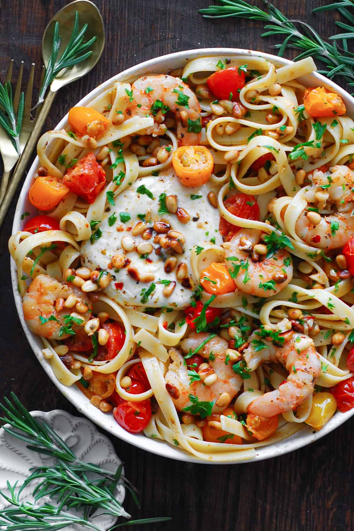 Mediterranean Shrimp Pasta with Cherry Tomatoes, Burrata Cheese, and Pine Nuts - on a white plate.