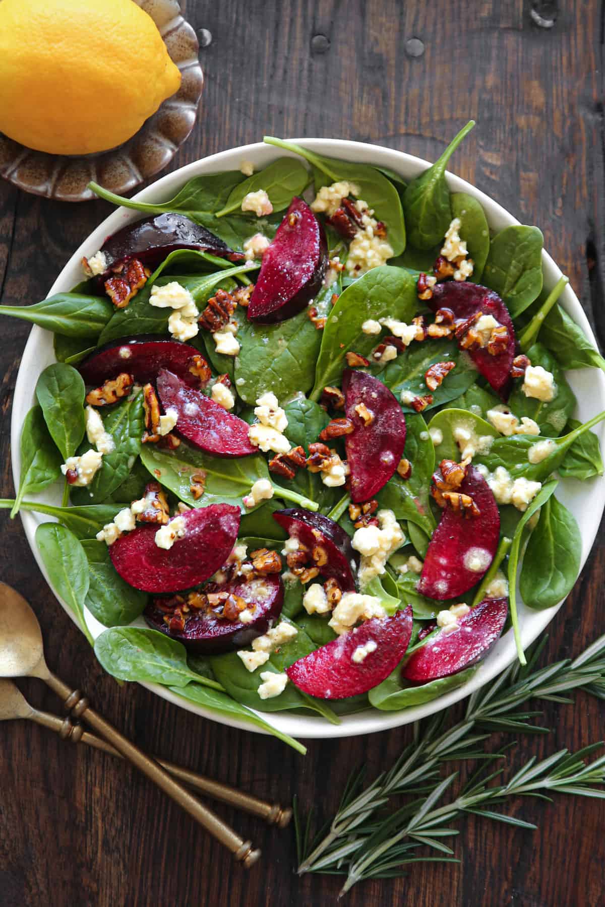 Plum Spinach Salad with Feta Cheese, Pecans, and Honey-Lemon Dressing - in a white bowl.