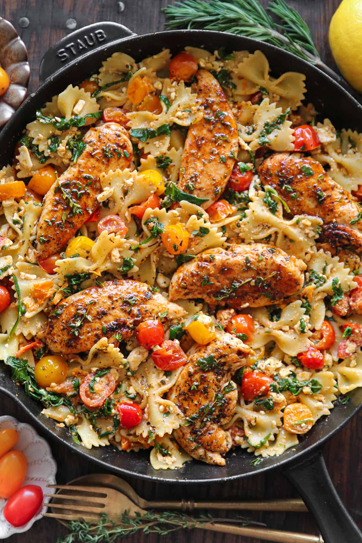 Chicken Feta Pasta with bow-tie pasta, tomatoes, and spinach - in a cast iron skillet.