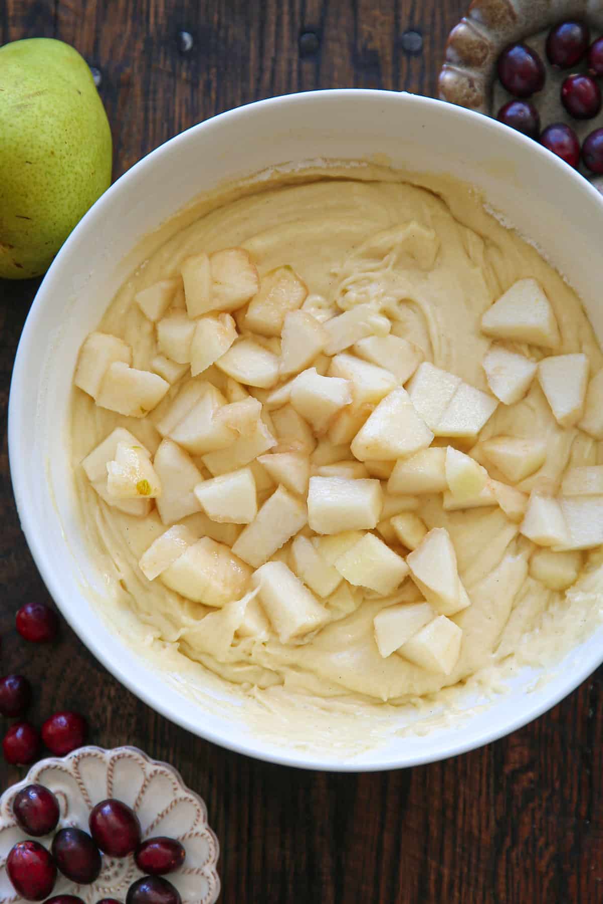 chopped peeled and cored pears in a cake batter in a mixing bowl.