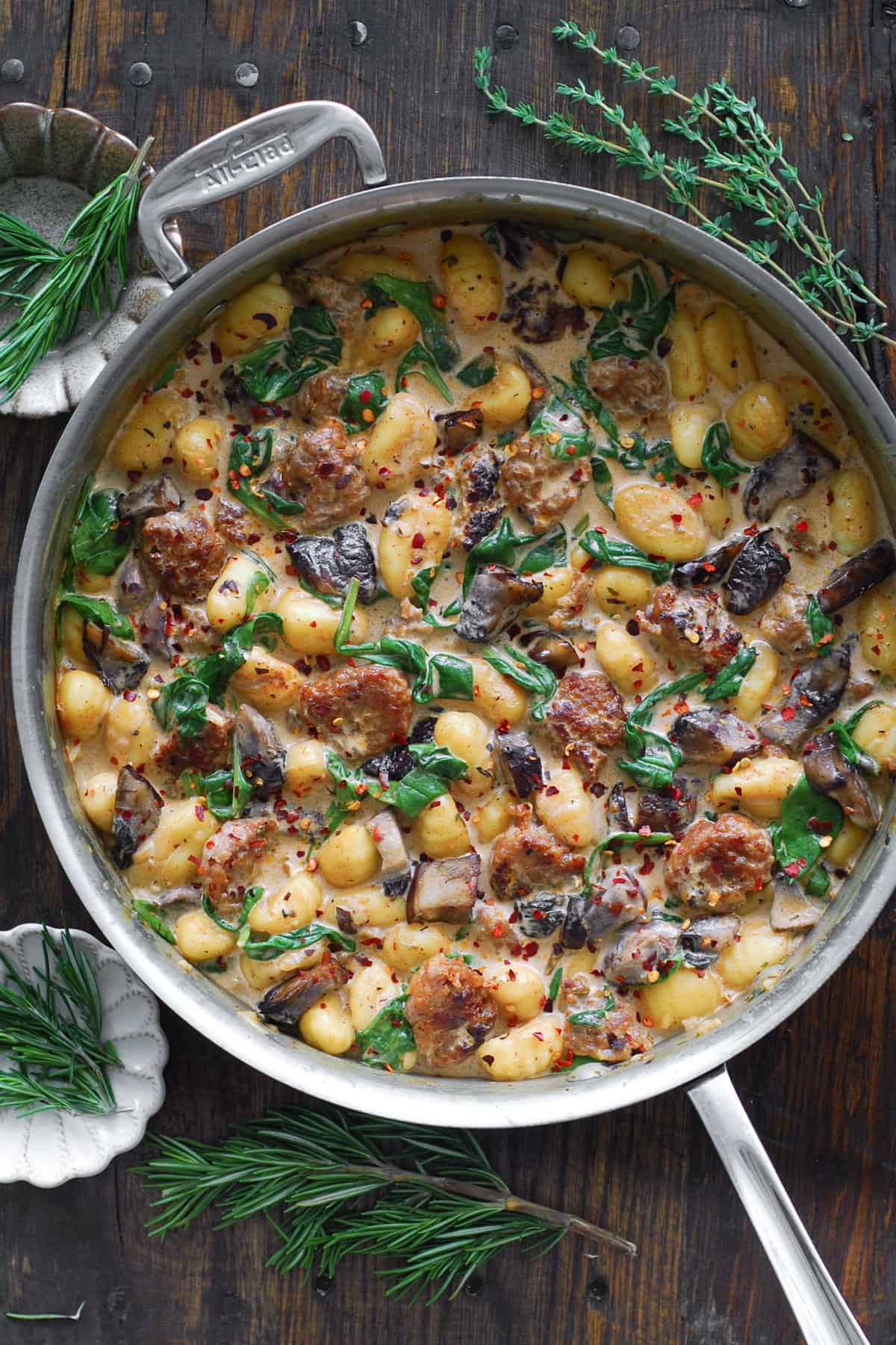 Creamy Gnocchi with Italian Sausage, Chopped Portobello Mushrooms, and Spinach - in a stainless steel skillet.