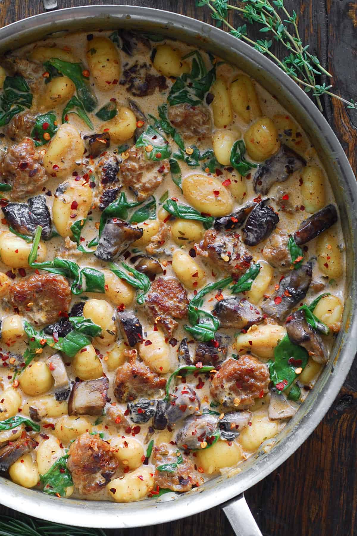 Creamy Gnocchi with Italian Sausage, Chopped Portobello Mushrooms, and Spinach - in a stainless steel pan.