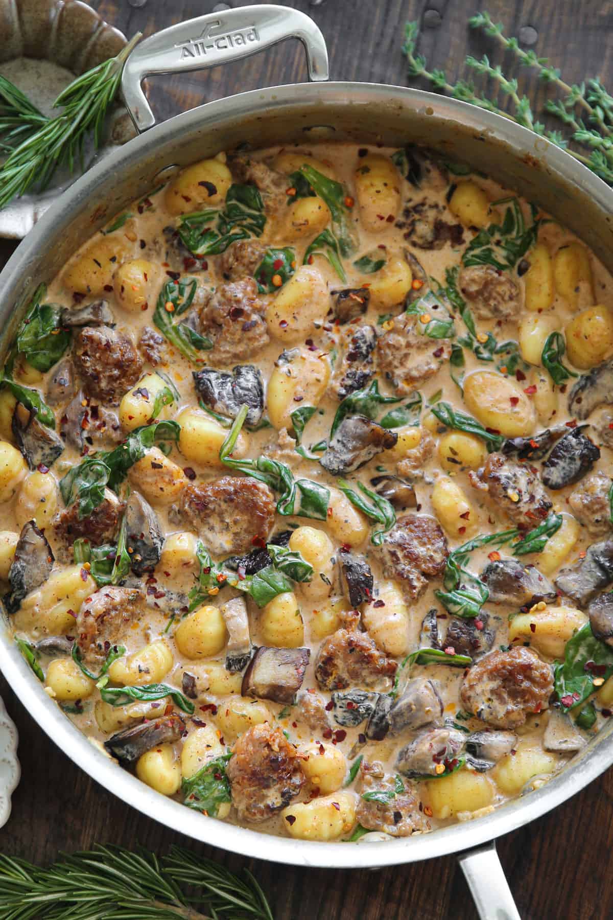 Creamy Gnocchi with Italian Sausage, Chopped Portobello Mushrooms, and Spinach - in a stainless steel skillet.
