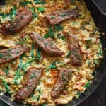 Flank Steak (sliced) with Creamy Orzo, Spinach, and Sun-Dried Tomatoes - in a cast iron skillet.