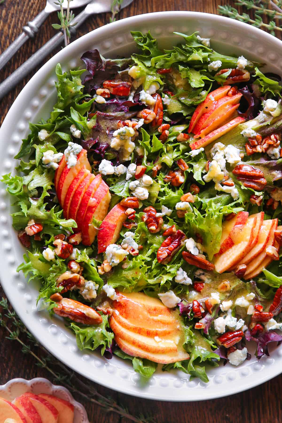 Green Salad with Apples, Blue Cheese, Pecans, Mixed Greens, and Honey-Lemon Dijon Mustard dressing - in a white bowl.