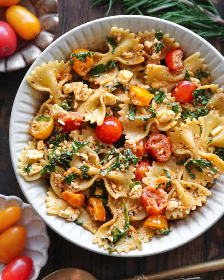 Pasta with Feta Cheese, Cherry Tomatoes, Spinach - in a white bowl.