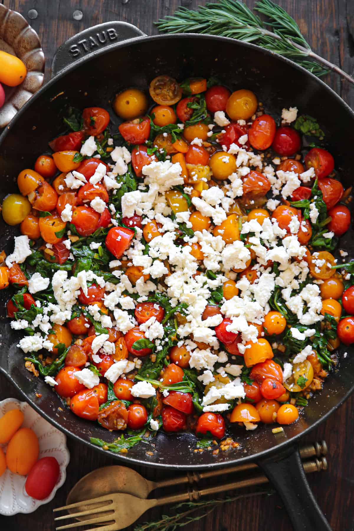 cooked cherry tomatoes with spinach and crumbled feta cheese - in a cast iron skillet.
