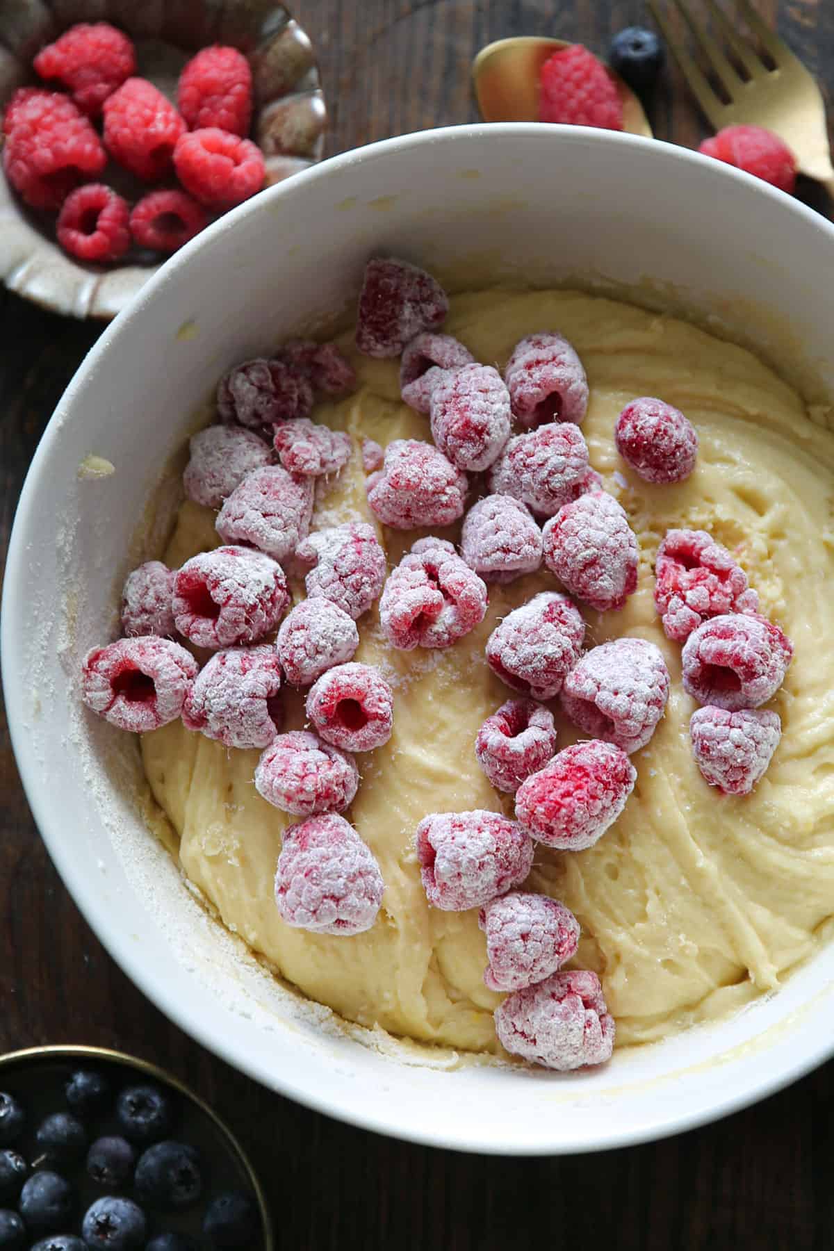 flour coated raspberries and cake batter in a bowl.