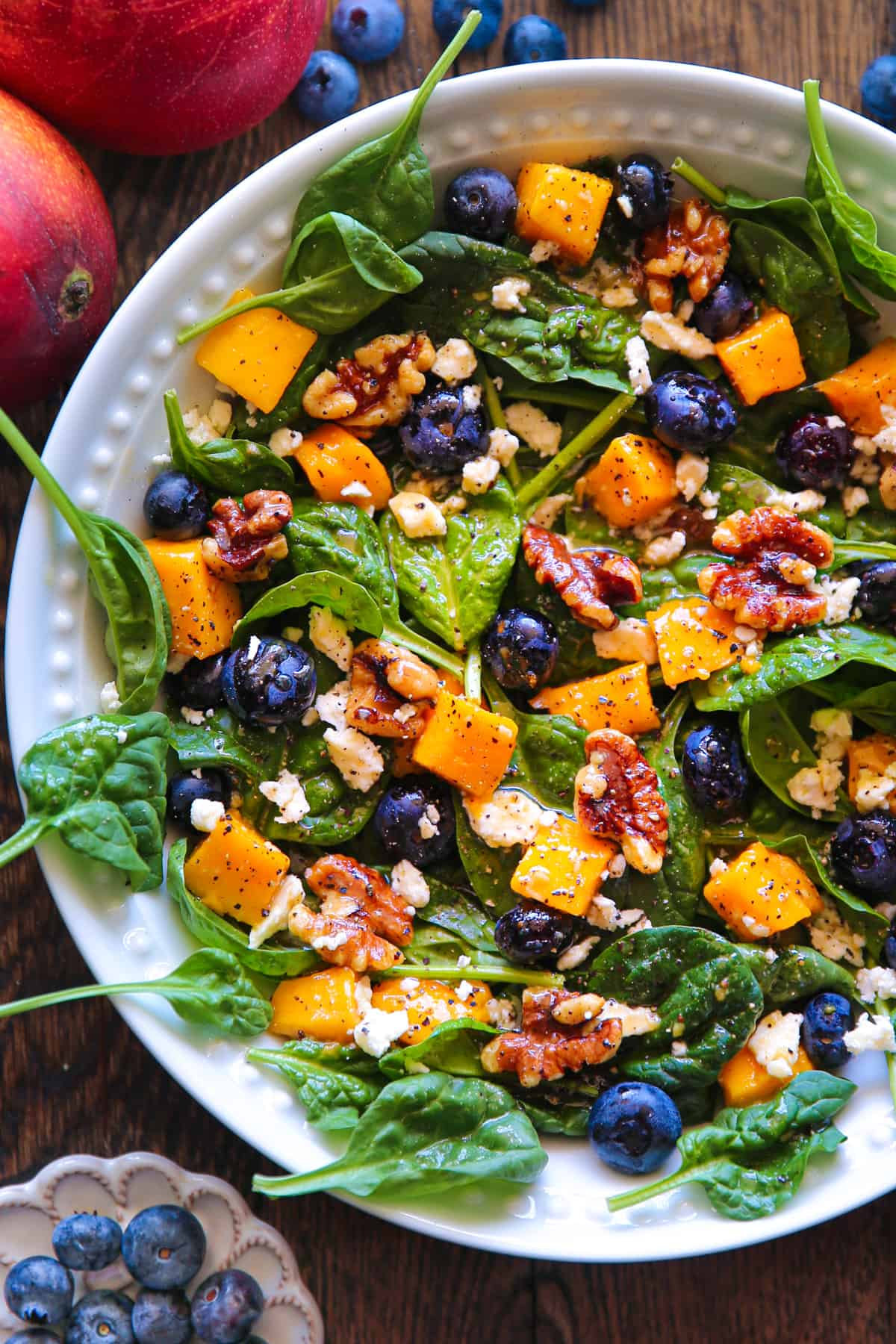 Mango Salad with Spinach, Blueberries, Walnuts, and Feta Cheese - in a white bowl.