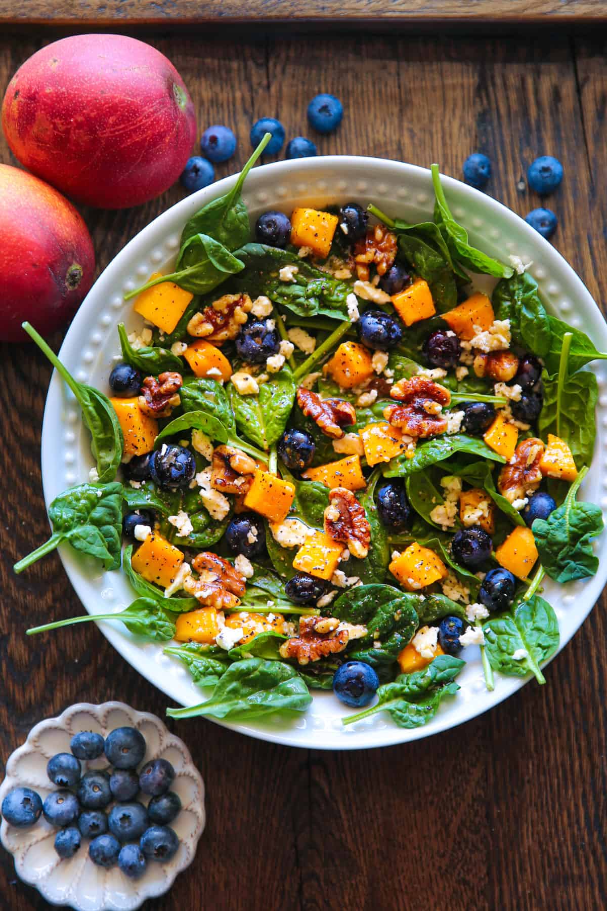 Mango Salad with Spinach, Blueberries, Walnuts, and Feta Cheese - in a white bowl.