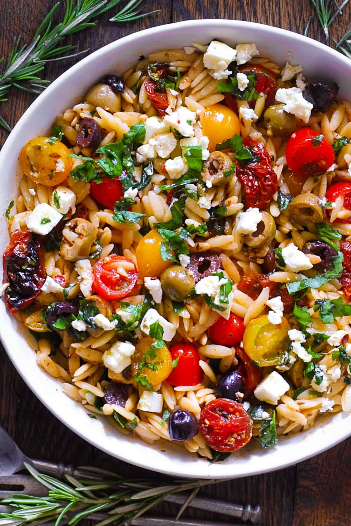 Greek Orzo with Tomatoes, Feta, and Olives - in a white bowl.
