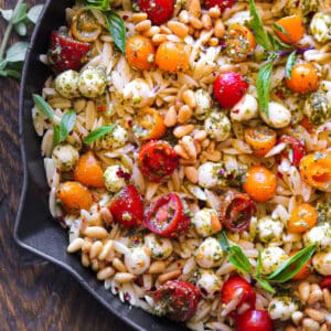 Pesto Orzo with tomatoes, mozzarella cheese and pine nuts - in a cast iron skillet.