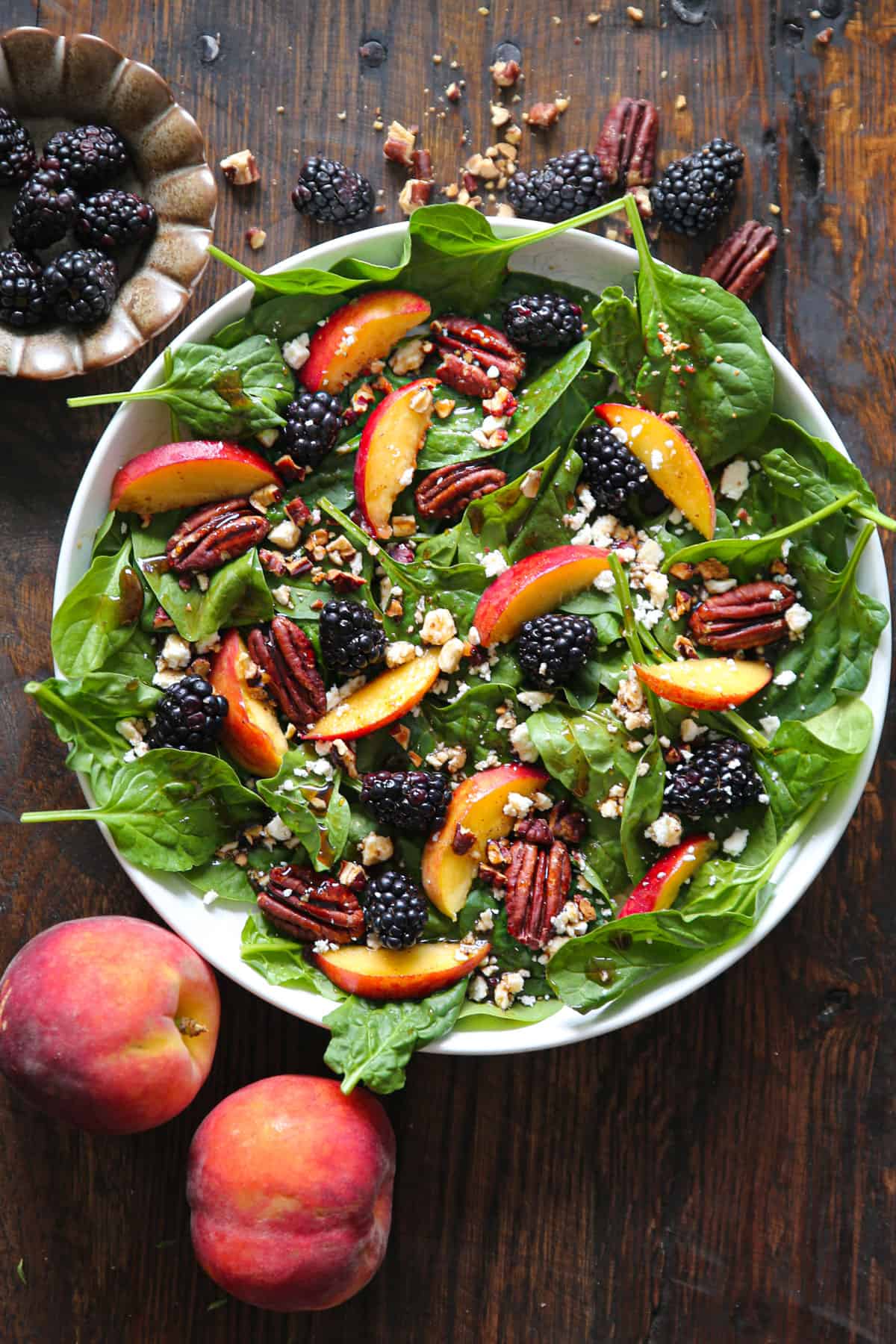 Summer Peach Spinach Salad with Blackberries, Pecans, Feta, and Balsamic Glaze - in a white bowl.