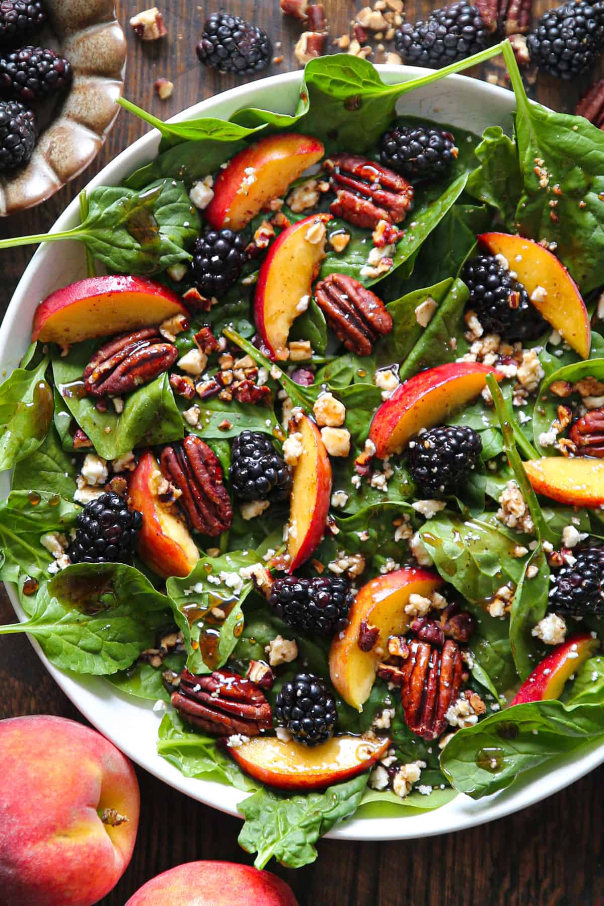 Summer Peach Spinach Salad with Blackberries, Pecans, Feta, and Balsamic Glaze - in a white bowl.
