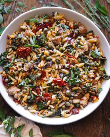 Sun-Dried Tomato and Spinach Orzo with Artichokes and Capers - in a white bowl.