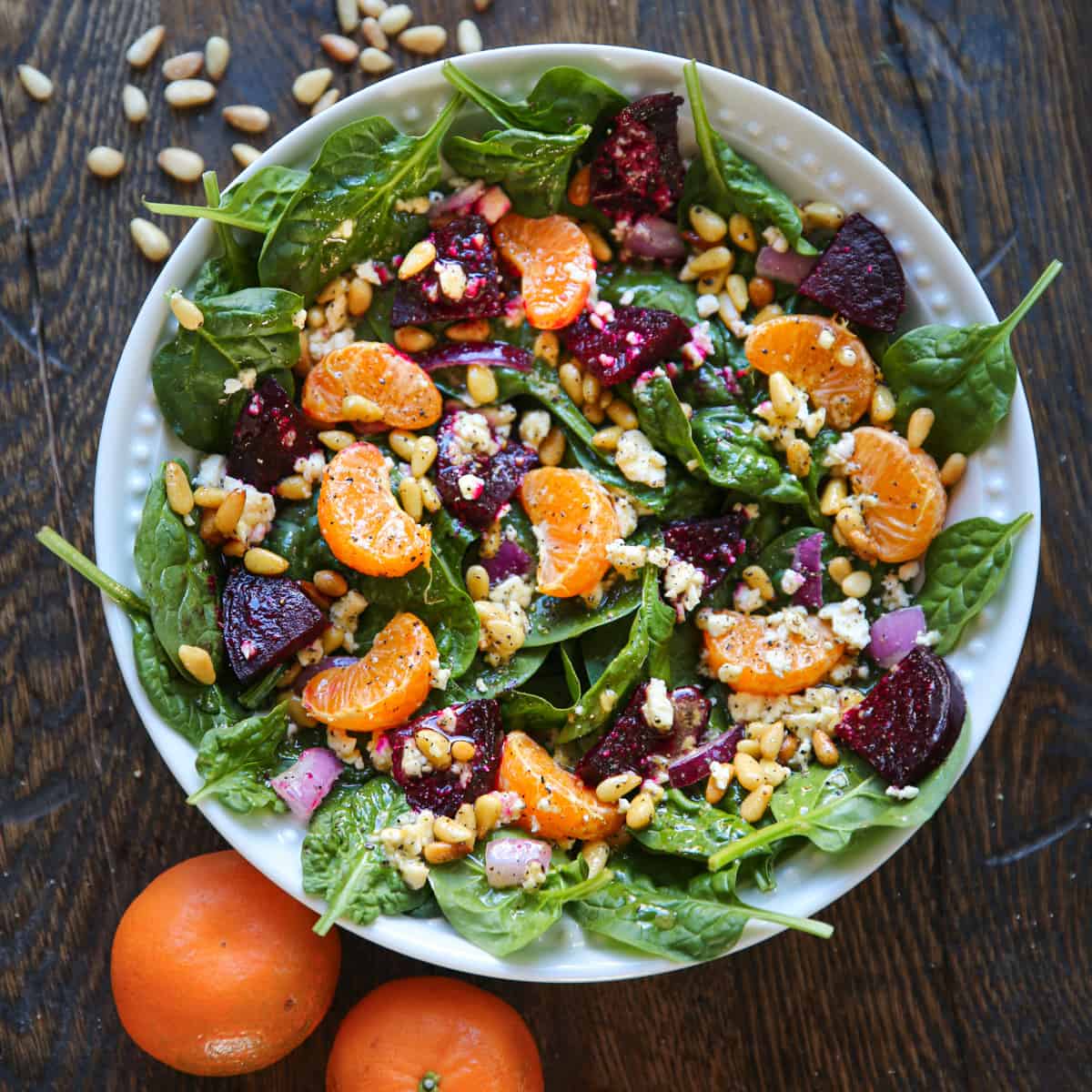 Beet Salad with spinach, mandarin oranges, red onion, pine nuts, feta cheese, and homemade Honey-Mustard Lemon Vinaigrette - in a white bowl.