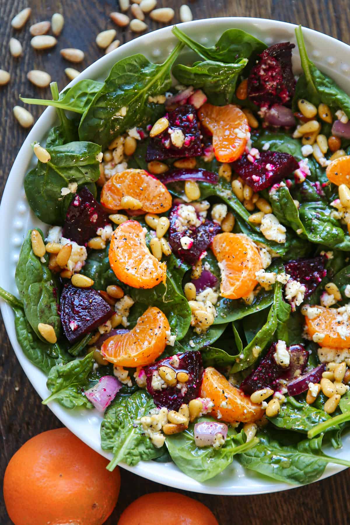 Beet Salad with spinach, mandarin oranges, red onion, pine nuts, feta cheese, and homemade Honey-Mustard Lemon Vinaigrette - in a white bowl.