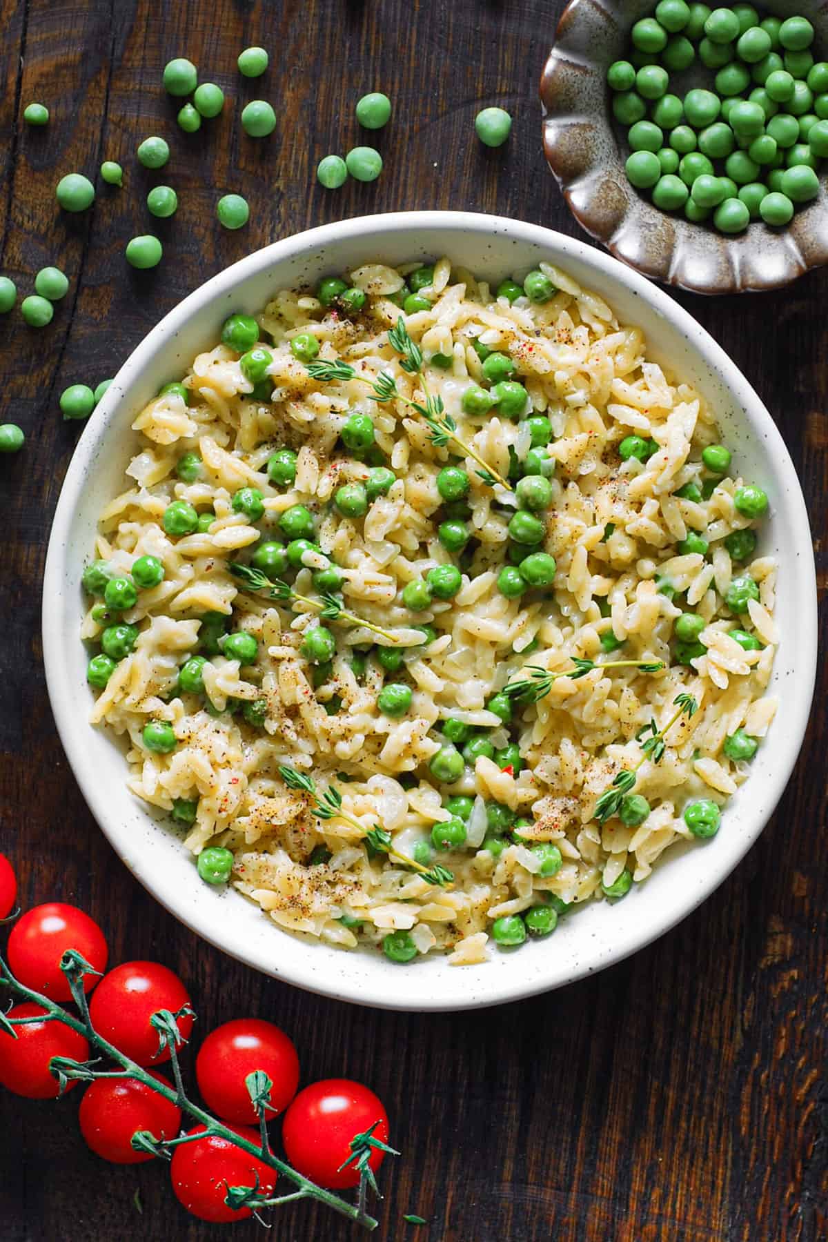 creamy garlic parmesan orzo with peas - in a white bowl.