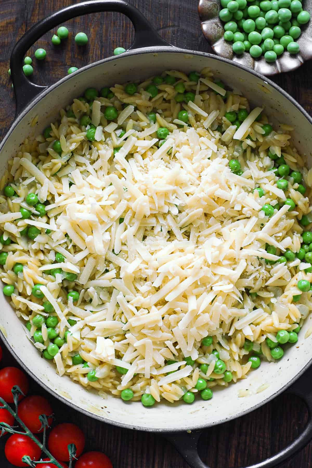 creamy orzo with peas and shredded parmesan cheese - in a pan.