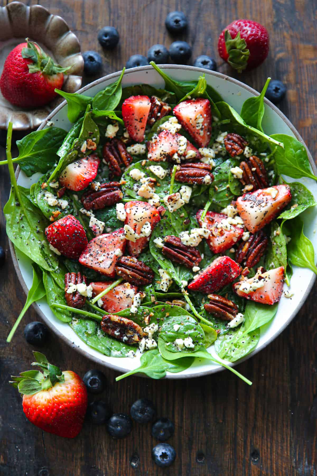 Strawberry Spinach Salad with Pecans, Feta Cheese, and Poppy Seed Honey Lemon Dressing - in a white bowl.