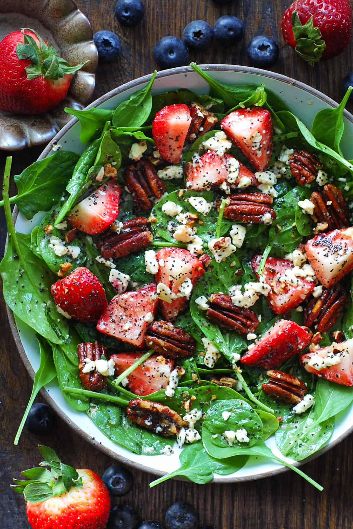 Strawberry Spinach Salad with Pecans, Feta Cheese, and Poppy Seed Honey Lemon Dressing - in a white bowl.