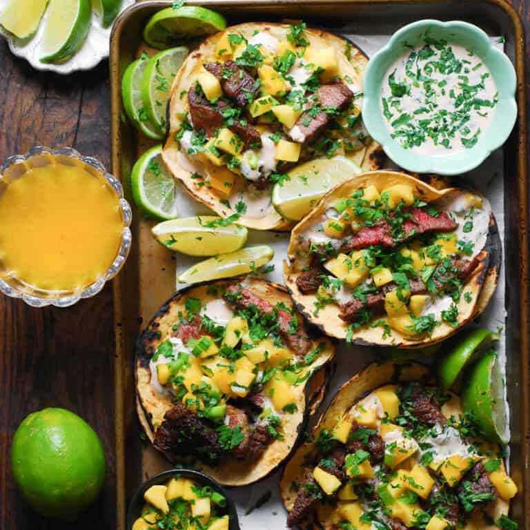 Steak Tacos with Mango Salsa and Spicy Cilantro-Lime Crema - on a baking sheet.