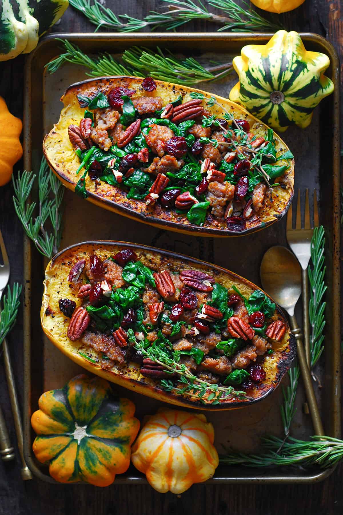 Spaghetti squash stuffed with sausage, spinach, cranberries and walnuts, on a baking sheet.