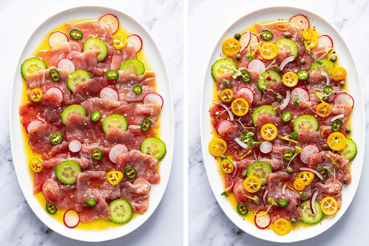 How to Make Tuna Crudo (Step-by-Step Photos) Two plates of thinly sliced raw fish are topped with cucumber, radish, jalapeño, oil, and citrus slices. The right plate has additional yellow tomatoes, capers, red onion, and fresh herbs on a white marble surface.
