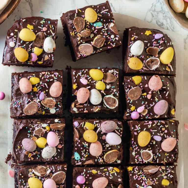 Festive Chocolate Easter Cake topped with Dark-Chocolate Ganache, Cadbury Mini-Eggs, and Easter pastel sprinkles (the cake is cut into squares).