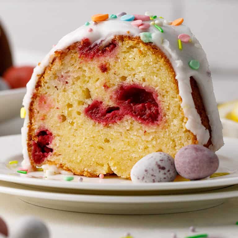 A slice of Lemon Raspberry Bundt Cake with Lemon Glaze (revealing juicy berries) - on a plate.